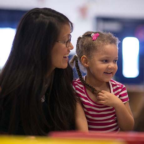 A smiling teacher with a Goddard School franchise student.